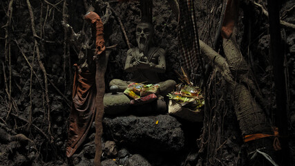Fototapeta na wymiar Religious place for rites with ancient statues of people in a dark cave with strong shadows