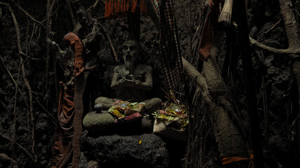 Fototapeta na wymiar Religious place for rites with ancient statues of people in a dark cave with strong shadows