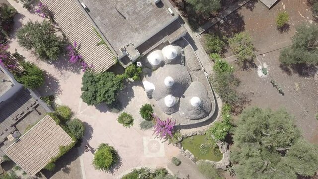 Aerial top down view of Trullo in Puglia Italy. Traditional italian white stone houses in olive grove. Ceglie Messapica, South Italy. Summer sunny day. Natural landscape.