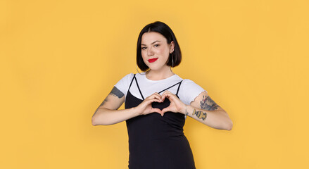 Young unusual woman with tattoos showing hands sign heart shape. Demonstration of love. Blogger followers concept. Hipster female share love.