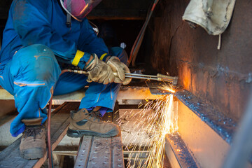 Worker cutting metal steels by Gas Cutting Torch. He cutting the iron plate in the confined spaced
