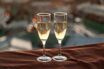 Two glasses of champagne on the background of city roofs at sunset
