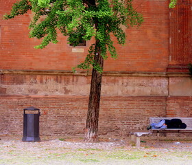 Unrecognizable person on the bench with a wall of red bricks in background, Bologna, Italy