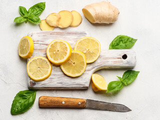 Lemon slices on a board with basil and ginger on the table.