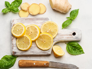 Lemon slices on a board with basil and ginger on the table.