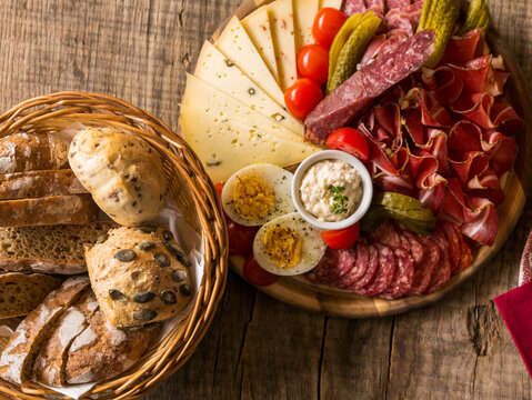 Close-up of an authentic lunch in South Tyrol, Italy during a hike in the Mountains. Tasty alpine kitchen. Bacon, bread, pepperoni on a wooden board.