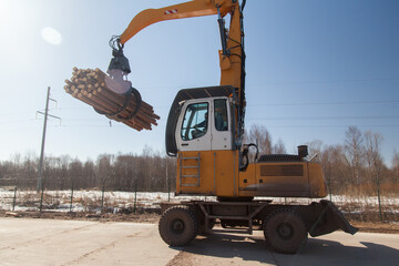 An industrial loader loads logs into a conveyor at a sawmill