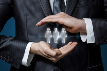 Businessman gesturing hands protects holograms of workers .
