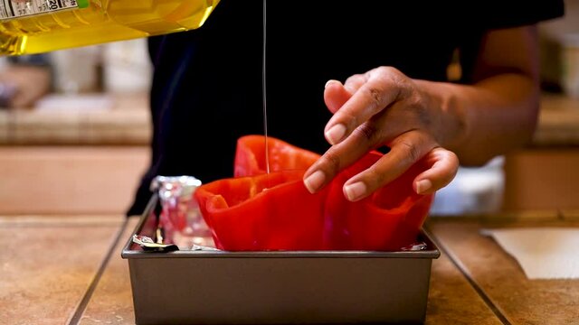 Pouring olive oil into red bell pepper shells to make a vegetarian stuffed pepper meal - slow motion