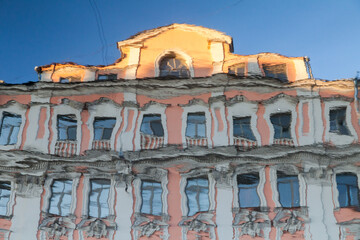 Facade of vintage house with old windows reflected in river