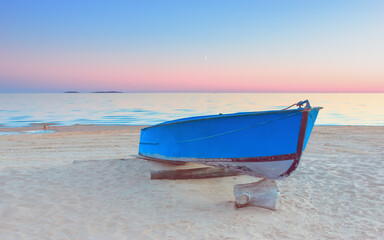 Fototapeta na wymiar Pink Sunset Seascape With A Blue Fishing Boat On A Beach
