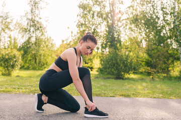 Portrait of active jogging woman resting and preparing shoes for training in park