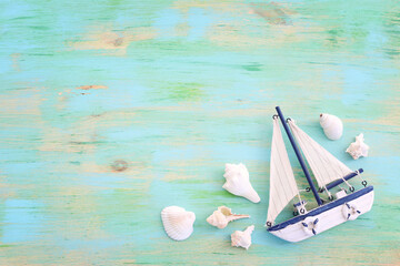 Fototapeta premium nautical concept with white decorative sail boat, seashells over blue wooden table and background