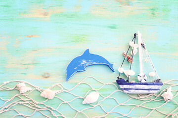 wooden vintage boat, dolphin, fishnet and sea shells over blue background