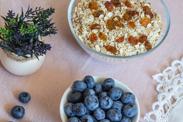 Bowls of granola, raisins,  and blueberries. Healthy breakfast every day. Copy space. Beige linen background. Flat lay