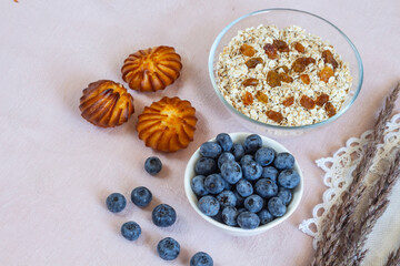 Bowls of granola, raisins,  and blueberries. Healthy breakfast every day. Copy space. Beige linen background. Flat lay