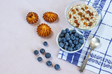 Bowls of granola, raisins,  and blueberries. Healthy breakfast every day. Copy space. Beige linen background. Flat lay
