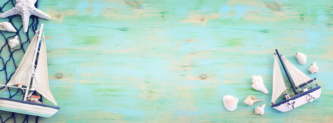 nautical concept with white decorative sail boat, seashells over blue wooden table and background