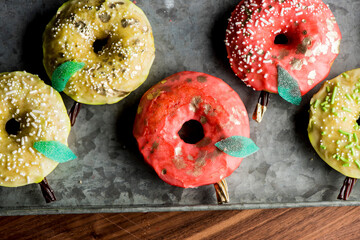 Doughnuts or donuts. Classic American favorite, apple cider donuts iced with maple syrup flavored butter cream frosting and topped with gold leaf sprinkles and decorations.