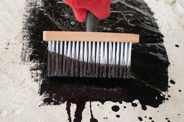 Roofer's hand in red mittens holding a brush