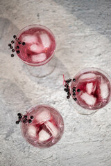 Cocktails with ice and black elder syrup, decorated with elderberries