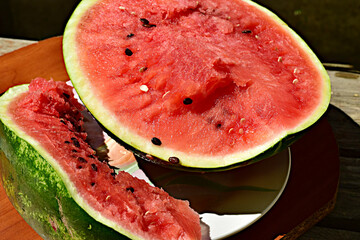 A shot of a ripe watermelon cut in half with black seeds.