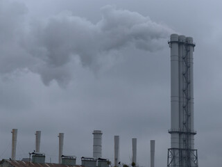 Smoke comes from industrial chimneys. The sky is covered with gray clouds. Environmental pollution.