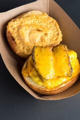 Breakfast sandwich. Bacon, fried egg, lettuce, tomato and onion on a bun being smashed by a waitresses hand. Action shot.