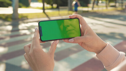 NEW YORK - 5 April 2018: Close up of woman hands holding and touching phone with green screen horizontal in the street people crosswalk background internet technology business message slow motion