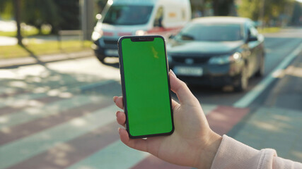 Lviv, Ukraine - May 19, 2018: In city center woman hands holding use touch phone with horizontal green screen street background sunset busy finger touch message cellphone display girl slow motion