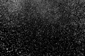 Abstract splashes of water on black background. Freeze motion of white particles. Rain, snow overlay texture.