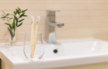 Eco bamboo toothbrushes in a glass in bathroom. Copy space