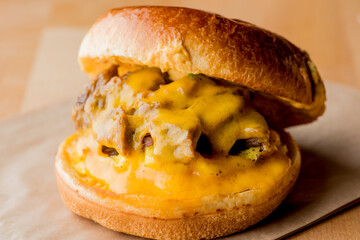 Breakfast sandwich. Bacon, fried egg, lettuce, tomato and onion on a bun being smashed by a waitresses hand. Action shot.