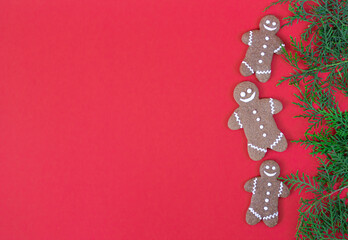 Christmas gingerbread cookies with green branches on red table top view. Greeting card concept. Space for text