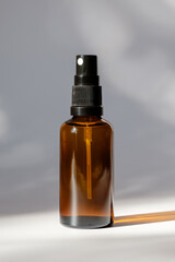 Cosmetic amber glass bottle with sprayer on white background. Natural organic perfume packaging design