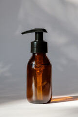 Cosmetic dark amber glass bottle on white background. Minimalist style pump dispenser, packaging design, branding