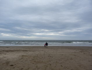 Father and son, walking in the sand to the horizon (far)