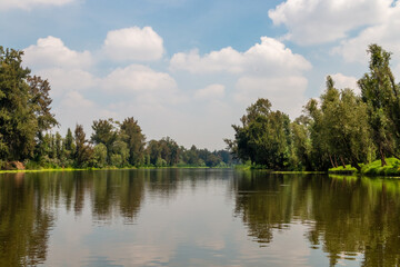 Fototapeta na wymiar Landscape of the Cuemanco canal in Xochimilco, Mexico City. Calm river. The river flows in spring through the forest.