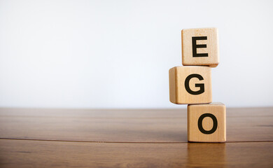 Concept word 'EGO' on cubes on a beautiful wooden table, white background. Business concept. Copy space.