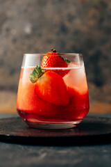 Delicious strawberry cocktail with ice on dark background