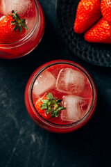  two strawberry cocktail with ice on dark background