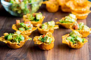 Spicy Guacamole served in crispy taco shells with salsas, cilantro and lime. Avocados diced and mixed with lemon and lime juices. Classic Tex-Mex, Mexican or American restaurant appetizer favorite.