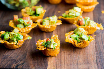 Spicy Guacamole served in crispy taco shells with salsas, cilantro and lime. Avocados diced and mixed with lemon and lime juices. Classic Tex-Mex, Mexican or American restaurant appetizer favorite.