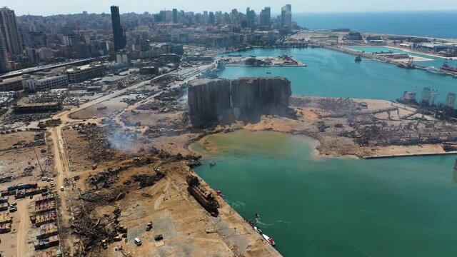 2020 Beirut port explosion: aerial aftermath of destruction, devastation, destroyed buildings ruined by ammonium nitrate blast in downtown industrial warehouse by ocean harbor, overhead drone approach
