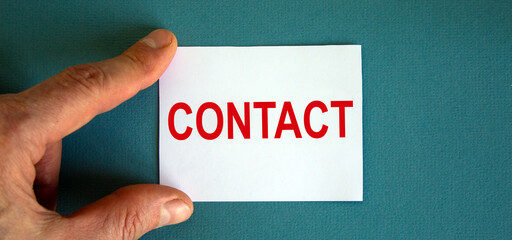 Word 'contact' on the white card between fingers. Beautiful blue background, business concept.