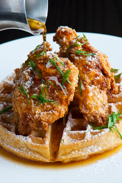 Chicken and waffles Classic American Diner Style Breakfast or Brunch menu item. Crispy homemade fried chicken on top of home buttermilk waffles topped with butter and maple syrup. 