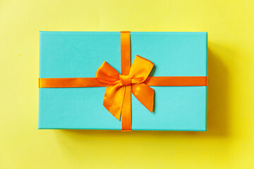 Christmas New Year birthday valentine celebration present romantic concept. Simply minimal design blue gift box isolated on yellow colorful background. Flat lay top view copy space.