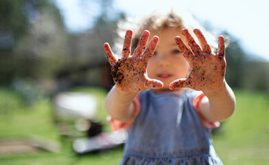 Small girl showing dirty hands outdoors in garden, sustainable lifestyle concept. - Powered by Adobe