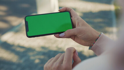 NEW YORK - 5 April 2018: Close up of woman hands holding and touching phone with green screen horizontal in the street sunlight car background internet technology business message slow motion