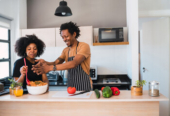 Afro couple cooking together in the kitchen.